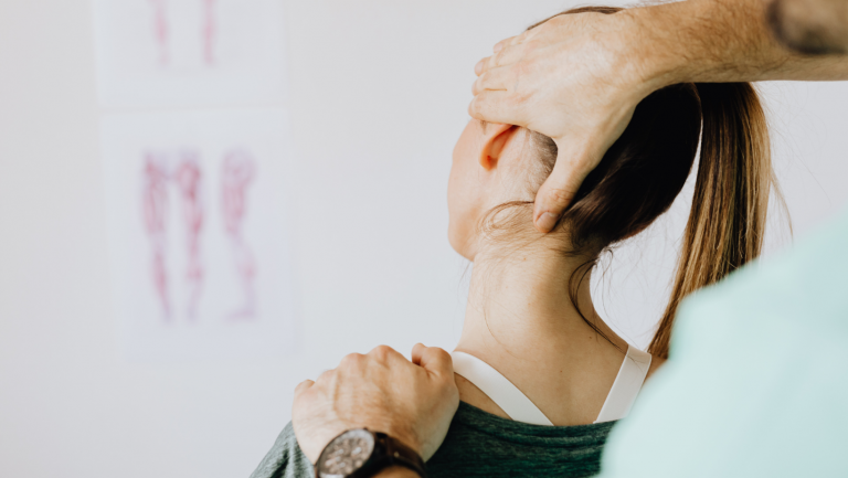 Chiropractor stretching a woman's neck to help treat her tension headaches and neck pain.