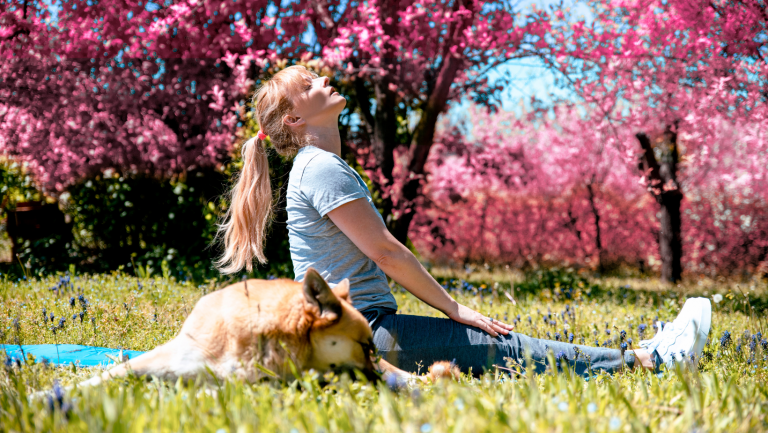 woman reducing her stress and back pain relief in a park with her dog after seeing an Orpington Chiropractor